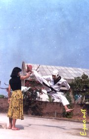 Mr. Khemchand executes an 'airborn joymala' kicking technique, while his wife holds the 'kick pad' for him